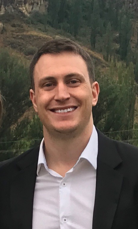 man named Cameron Wills in a suit with a forest in behind him